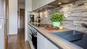 Une cuisine moderne avec un pare-feu en pierre, un évier encastré et un plan de travail agrémenté de légumes frais et d’une plante en pot.