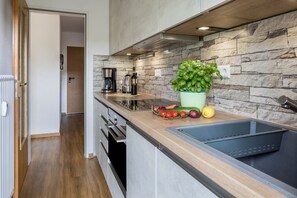 Una cocina moderna con protector contra salpicaduras de piedra, un lavamanos integrado y una encimera con verduras frescas y una planta en maceta.