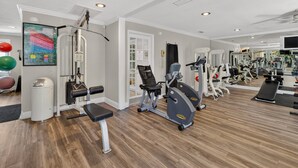 Un gimnasio con equipos de ejercicio variados, un espejo y una pantalla montada en la pared.