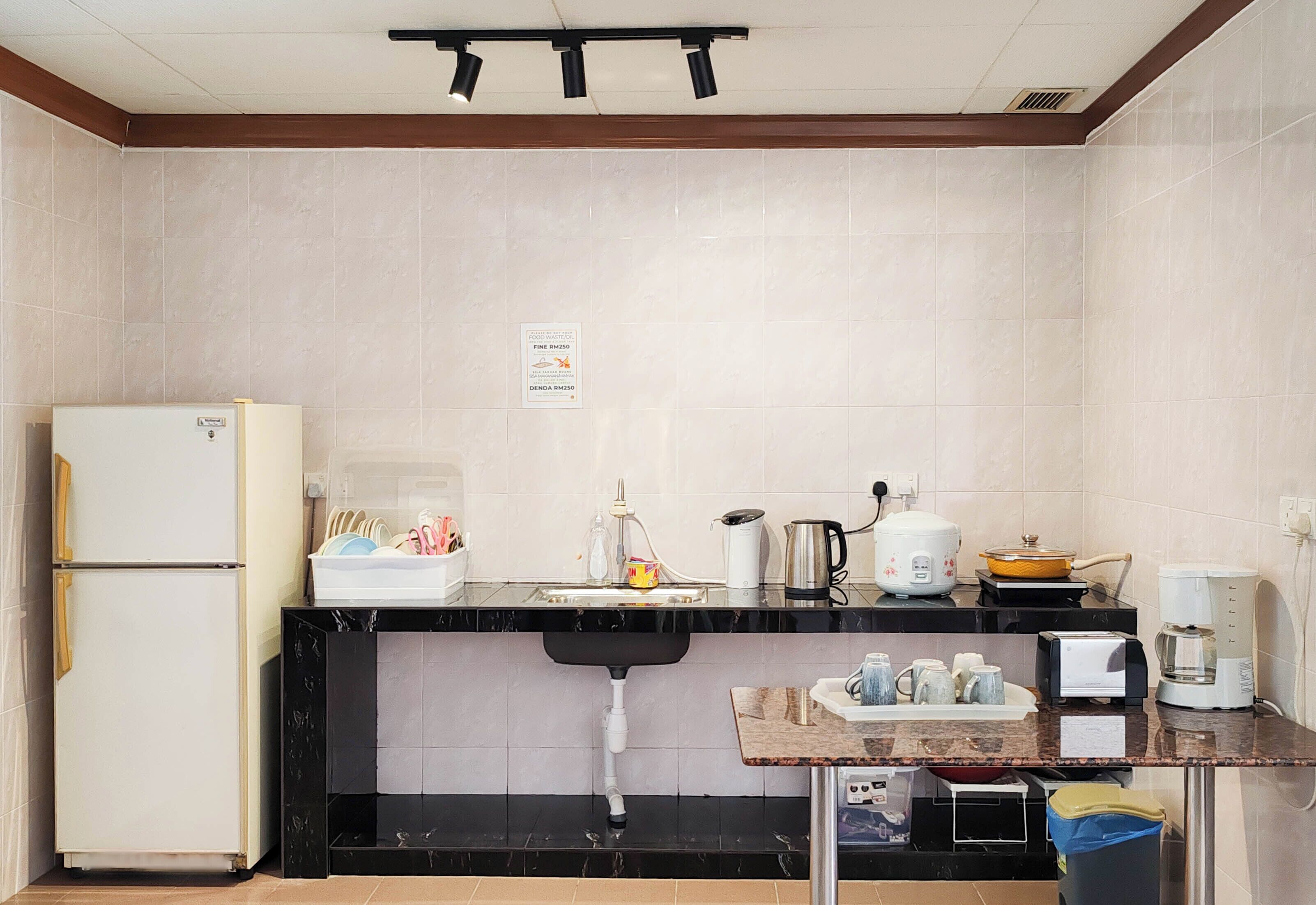 A kitchen with a refrigerator, sink, countertop, and various appliances including a coffee maker and a toaster.