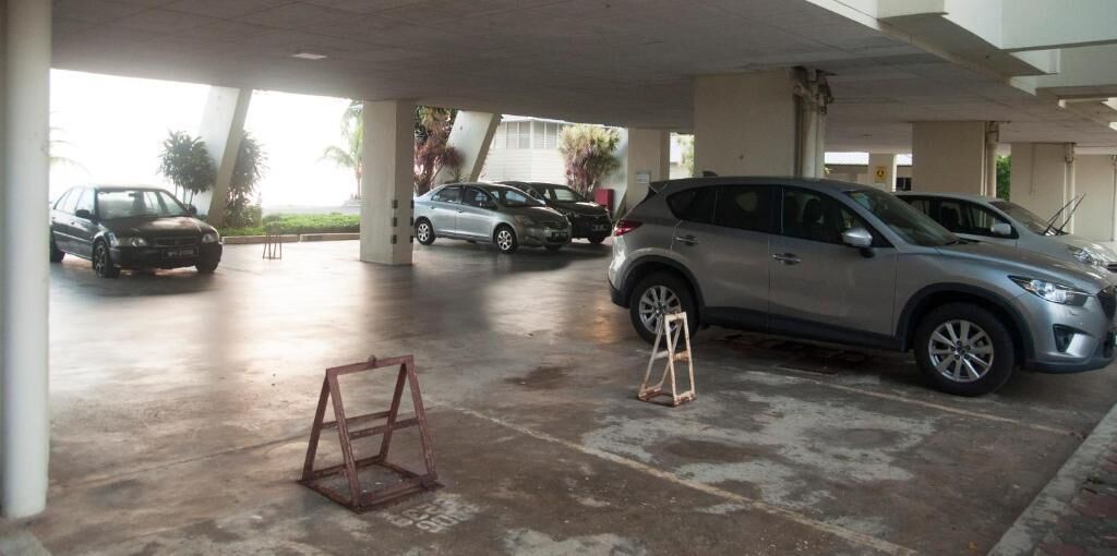 A parking garage with multiple cars parked under a large overhang.