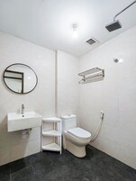 Un baño moderno con lavamanos, inodoro y ducha.