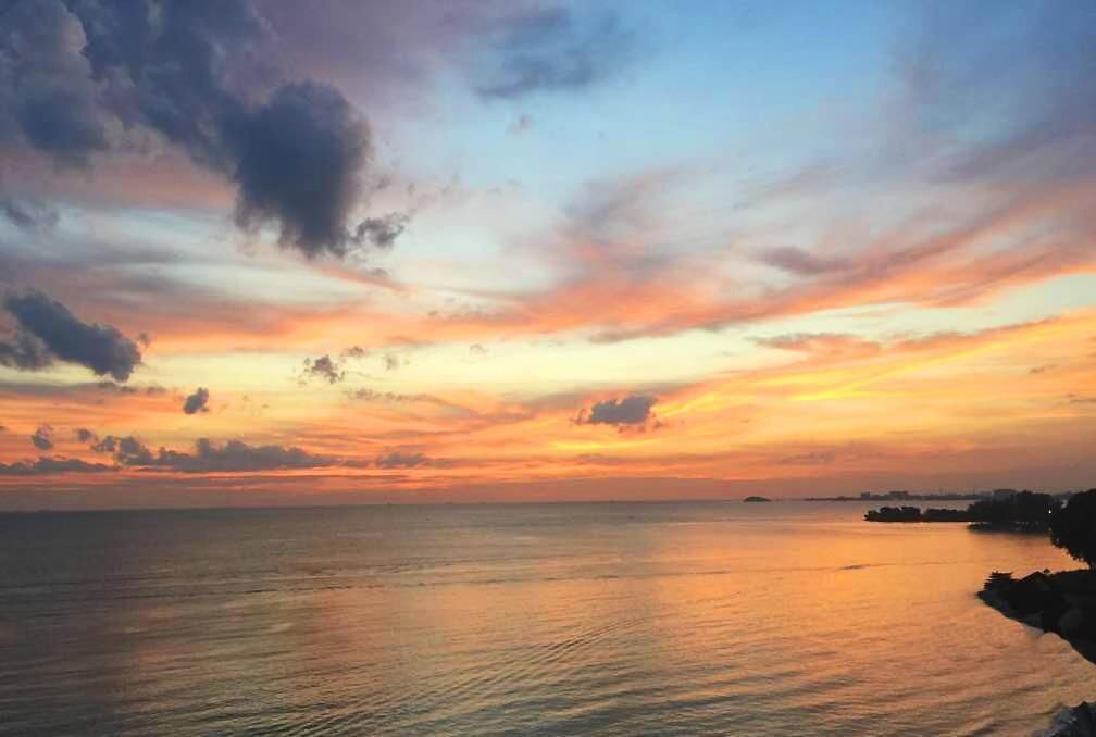 A coastal sunset with calm waters reflecting the sky.