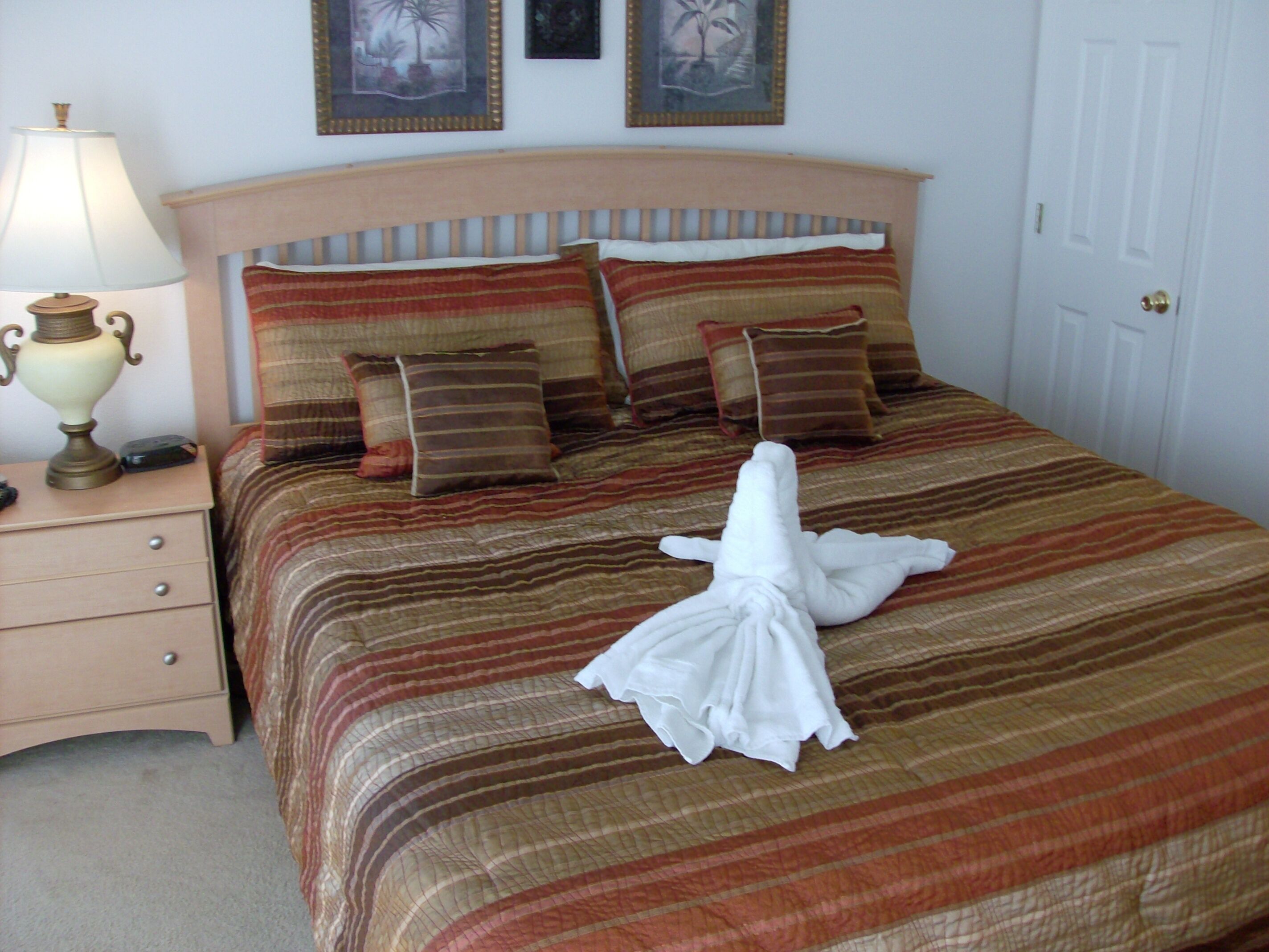 A neatly made bed with striped bedding, a bedside lamp, and a folded towel on the bed.