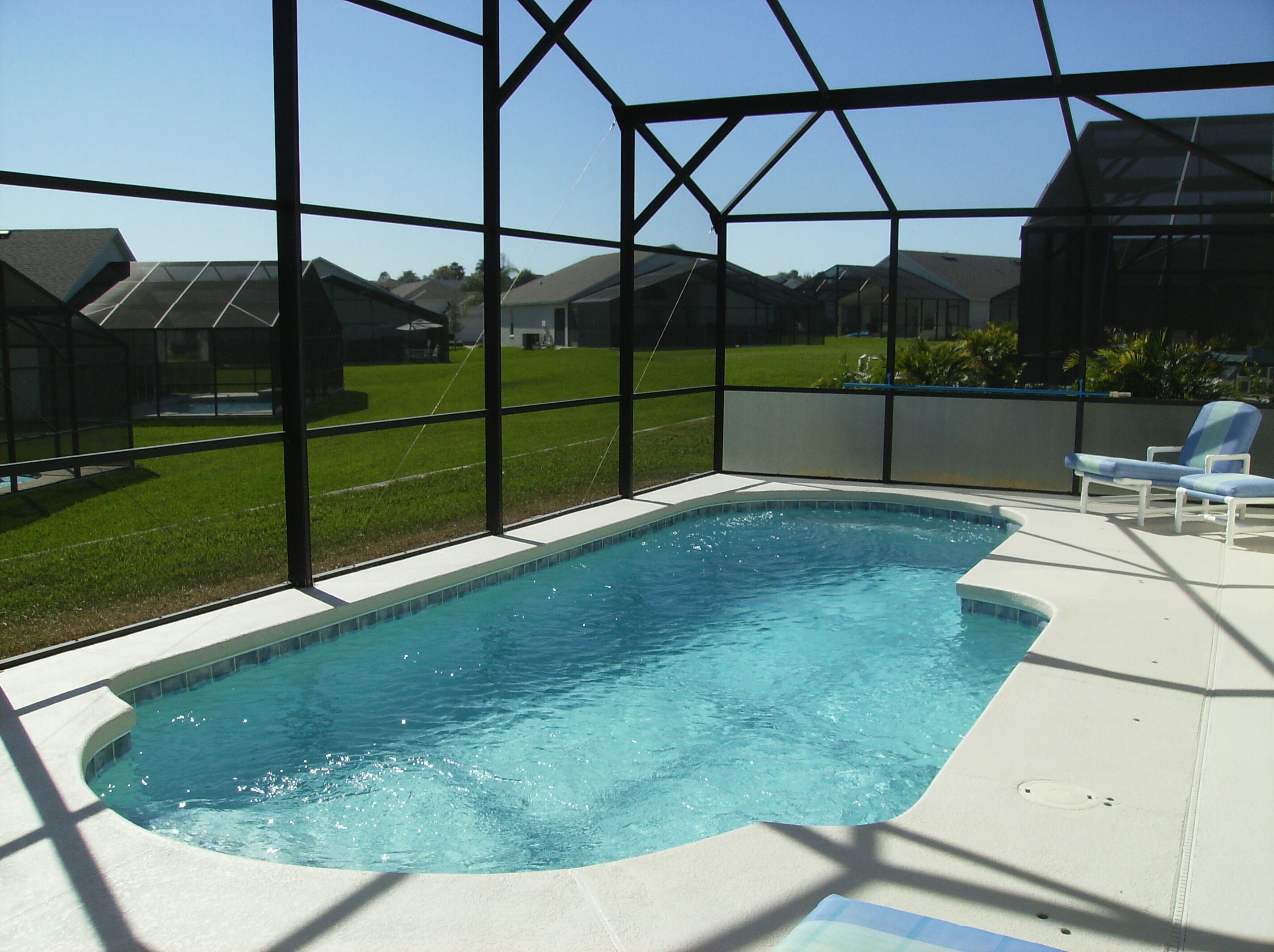 A swimming pool with a clear view of the surrounding houses through large windows.