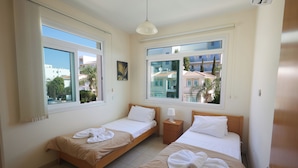 Una habitación de hotel con dos camas, una ventana, una mesita de noche y una puerta.