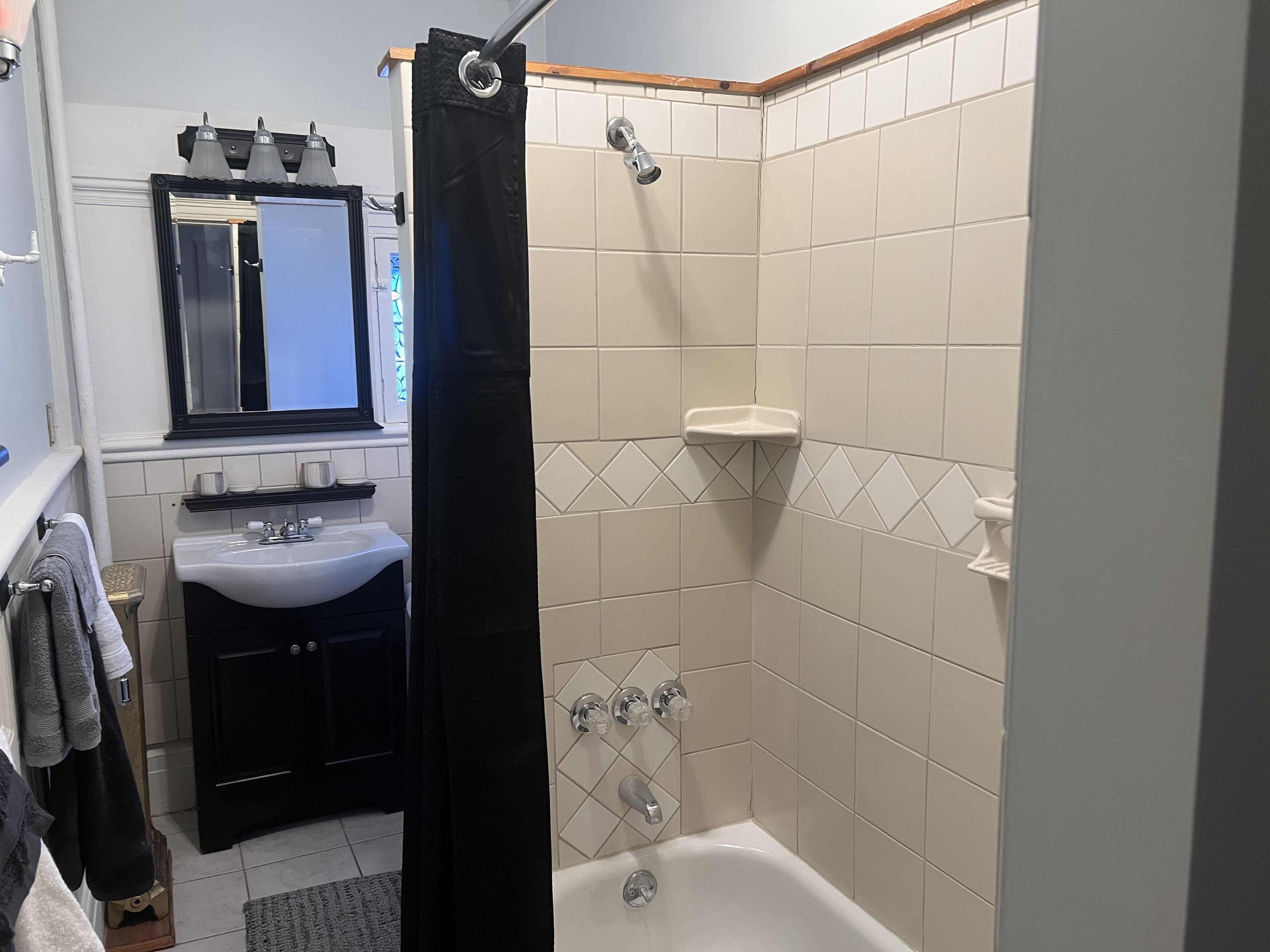 A bathroom with a sink, mirror, and shower.