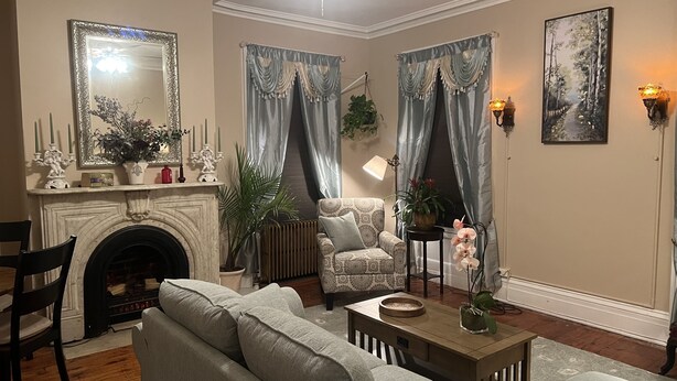 Una sala de estar con chimenea, sillones estampados, un sofá y una mesa de centro.