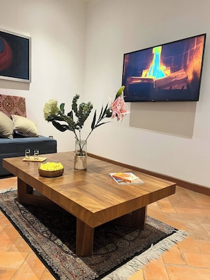 A living room with a wooden coffee table, a vase with flowers, a flat-screen TV, and a patterned rug. - Malen House San Miguel de Allende Mexico (San Miguel de Allende)