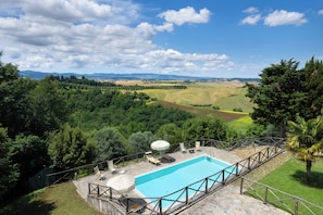 A pool with a view of a green landscape and distant mountains.