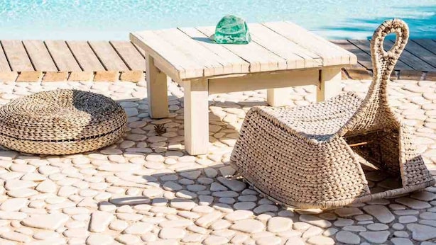 A poolside area with a wooden table and woven chairs, overlooking a coastal town with buildings and a clear blue sea. - Paraga Scorpios Villa1 hot tub 7 Mins Walk to Beach by Calypso Sunset Villas (Mykonos)