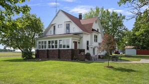 A two-story house with a red door, a covered porch, and a brick foundation.