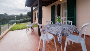 An outdoor patio with a table and chairs, a vase with flowers, and a view of the surrounding landscape. - APPARTAMENTI CAMPO AL PERO - CAMPO AL PERO - BILO 2 (Rio dell'Elba)