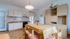 A compact kitchen with white cabinets, a wooden dining table with floral tablecloths, and a hanging pendant light. - APPARTAMENTI CAMPO AL PERO - CAMPO AL PERO - TRILO 3 (Rio dell'Elba)
