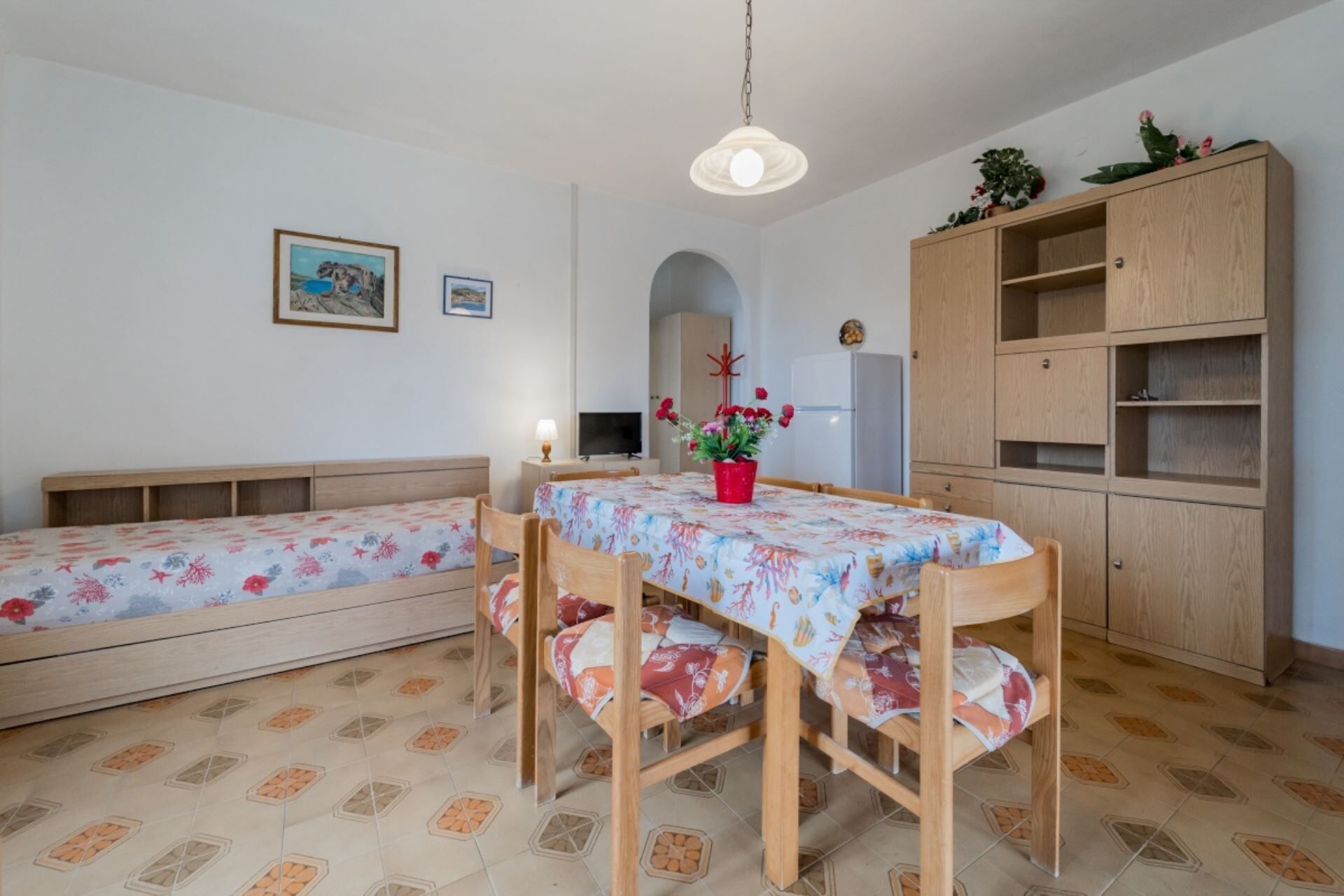 A dining area with a table and benches, a cabinet, and a TV.