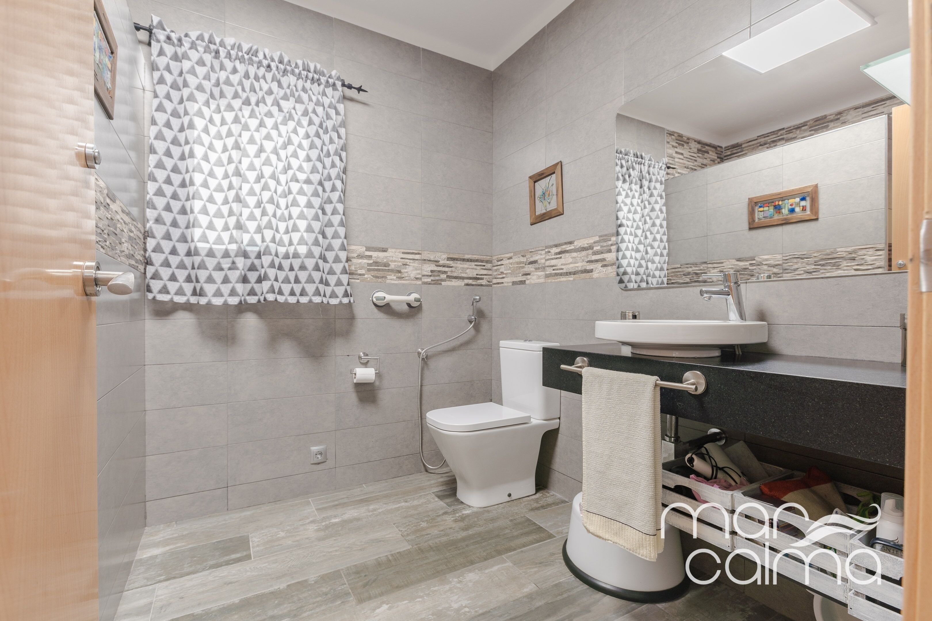A modern bathroom with a shower, toilet, and sink.
