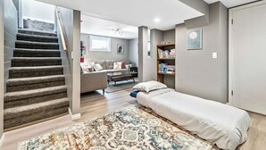 Une chambre moderne comprenant un lit, un escalier, un coin salon avec un canapé et une table basse, ainsi qu’une bibliothèque.