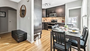 Une cuisine moderne avec des meubles de couleur sombre, un four à micro-ondes et un coin repas avec une table dressée pour quatre personnes.