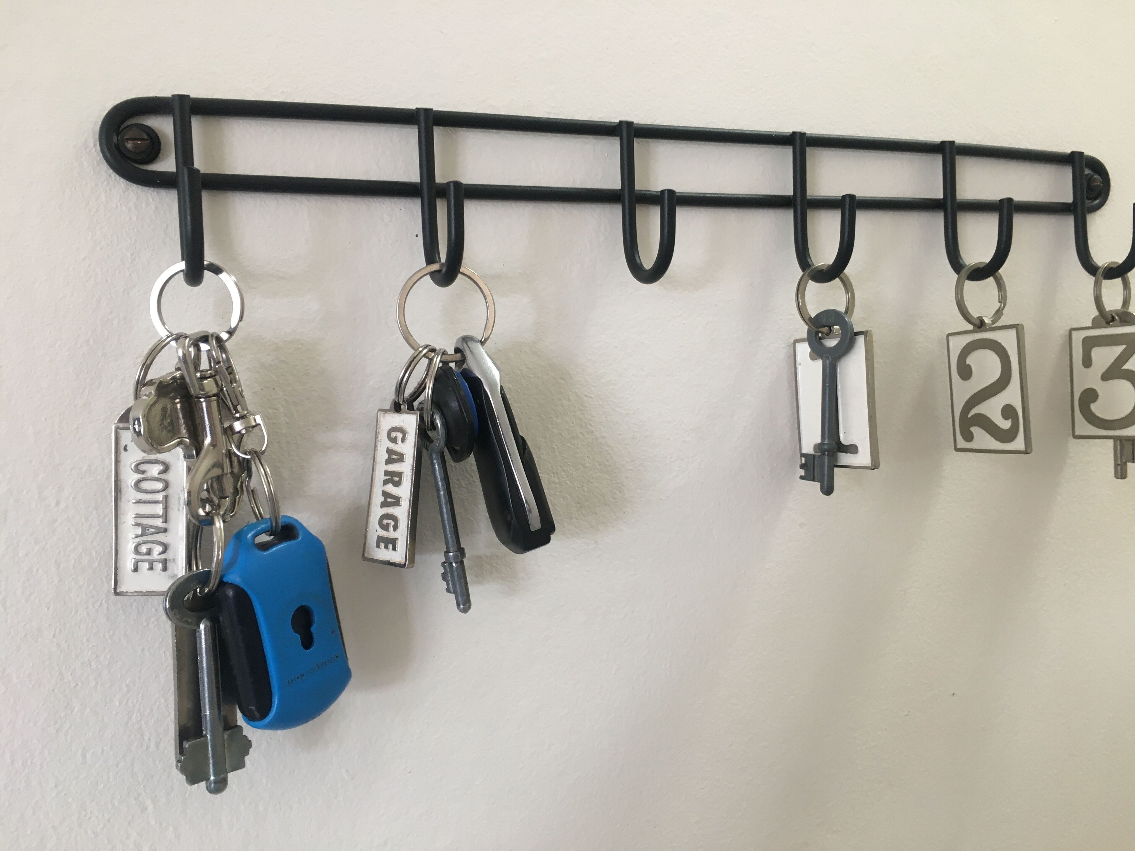 A wall-mounted key rack with keys and locks, including labels for 'COTTAGE' and 'GARAGE'.