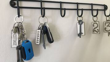 A wall-mounted key rack with keys and locks, including labels for 'COTTAGE' and 'GARAGE'.