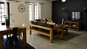 Ein Wohnzimmer mit einer Couch, einem Couchtisch, einem Fernseher und einem Essbereich mit Stühlen und einem Tisch.