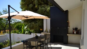 Eine Terrasse im Freien mit Tisch, Stühlen und einem Grill.