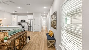 A modern kitchen with white cabinets, stainless steel appliances, and a wooden dining table.