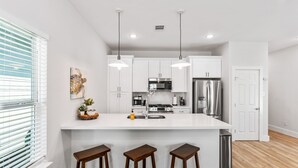 A modern kitchen with white cabinets, stainless steel appliances, and a central island with stools.