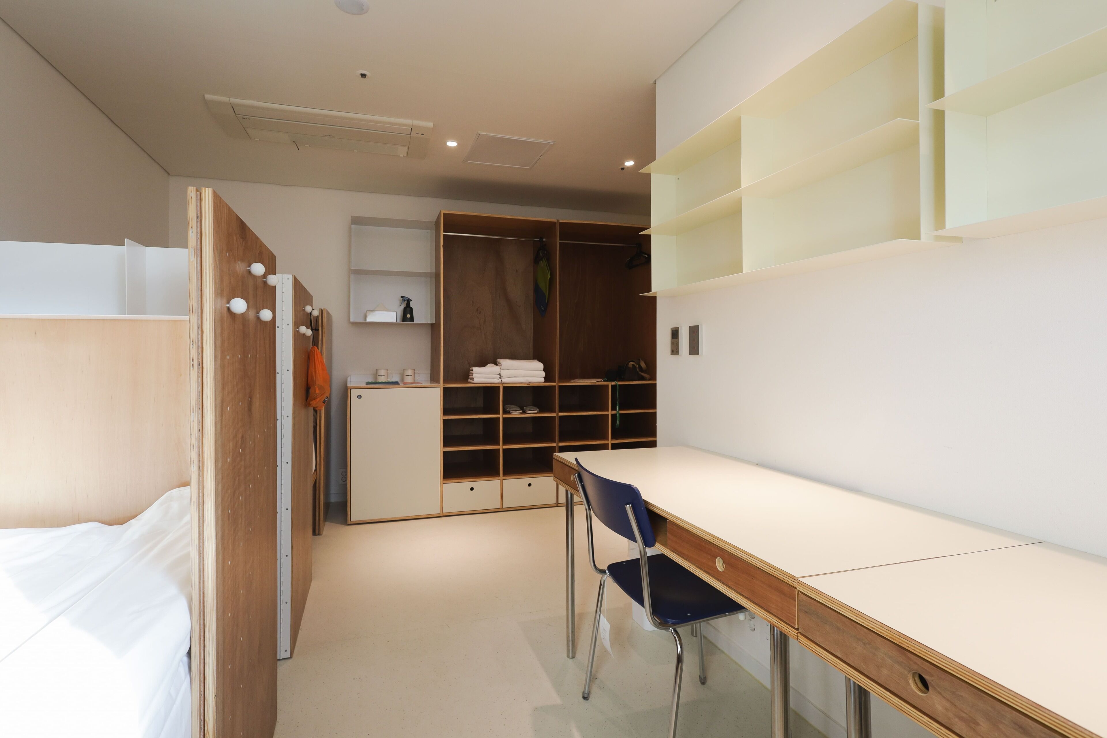 Een moderne slaapkamer met een bed, een bureau en een kledingkast.