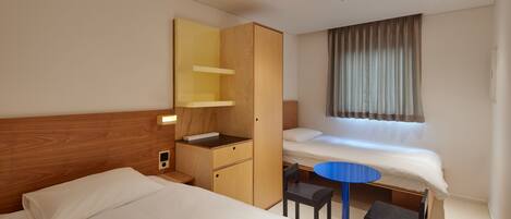 Une chambre d’hôtel avec deux lits, une armoire en bois, un petit bureau avec une chaise et une table ronde.