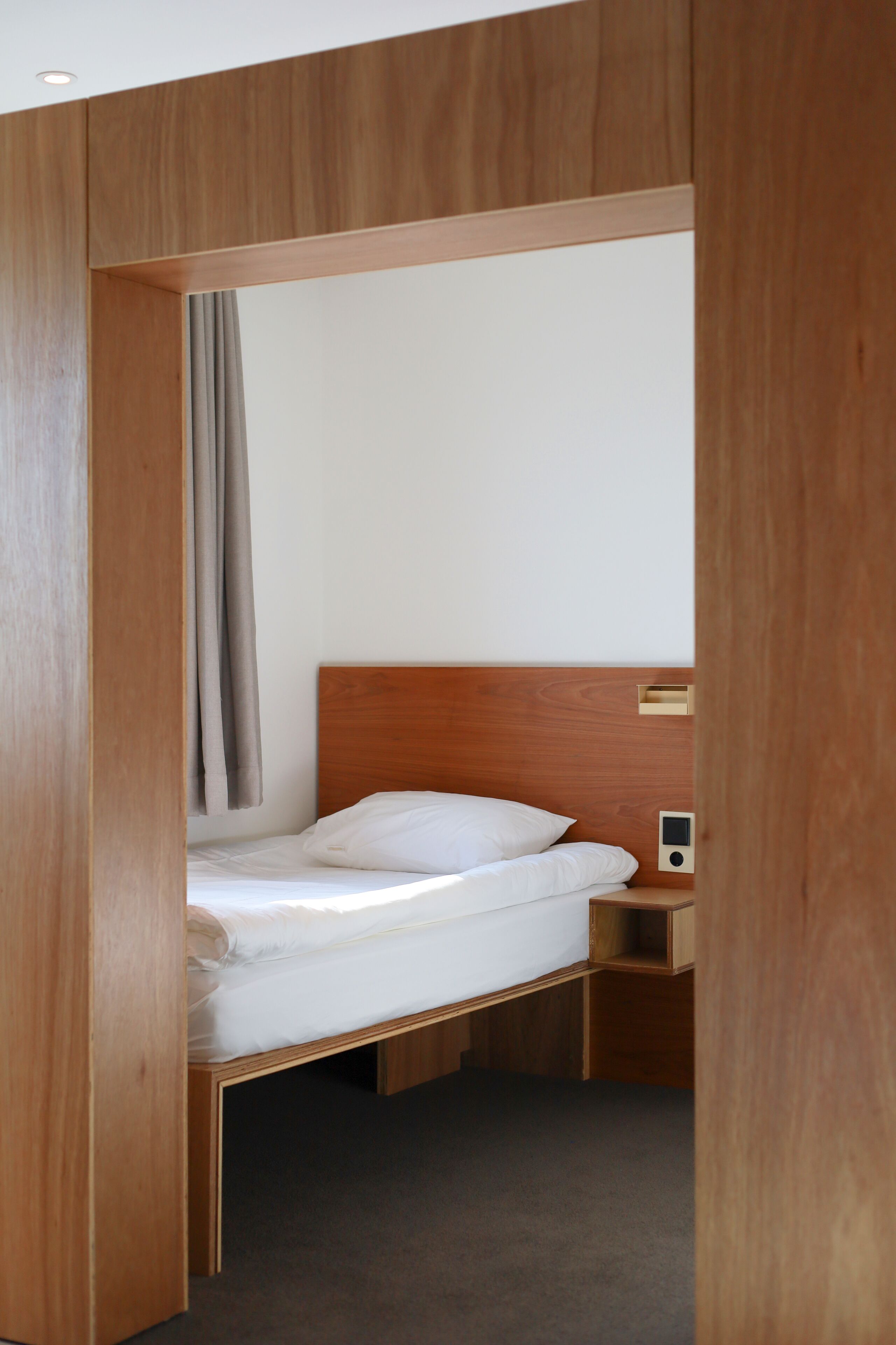 Un lit simple avec une tête de lit en bois, une table de chevet et une petite commode.