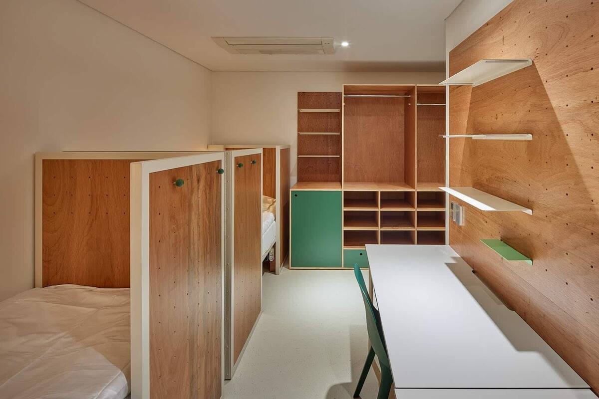 A modern, minimalist room with a bunk bed, a desk, and built-in shelving.