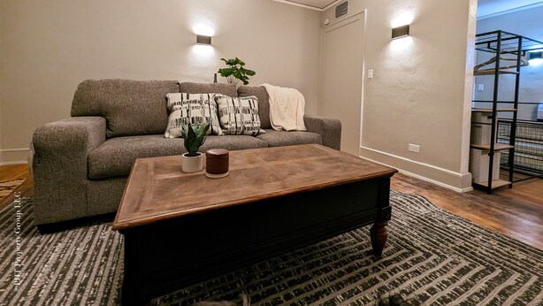A living room with a grey sofa, a wooden coffee table, a patterned rug, and two wall-mounted lights. - Contemporary Style  (Florence)