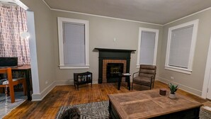 A living room with a fireplace, a wooden floor, a brown leather chair, and a small table with a plant. - Contemporary Style  (Florence)
