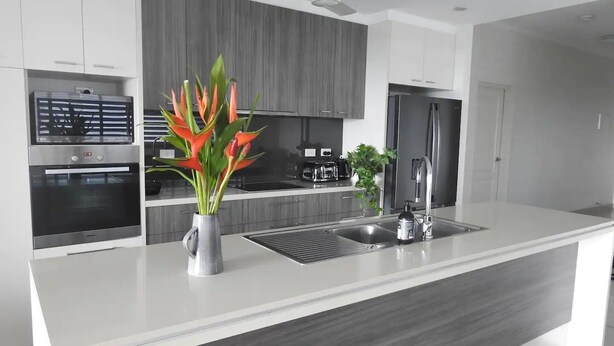 Una cocina moderna con una isla central, electrodomésticos de acero inoxidable y un ventilador de techo.