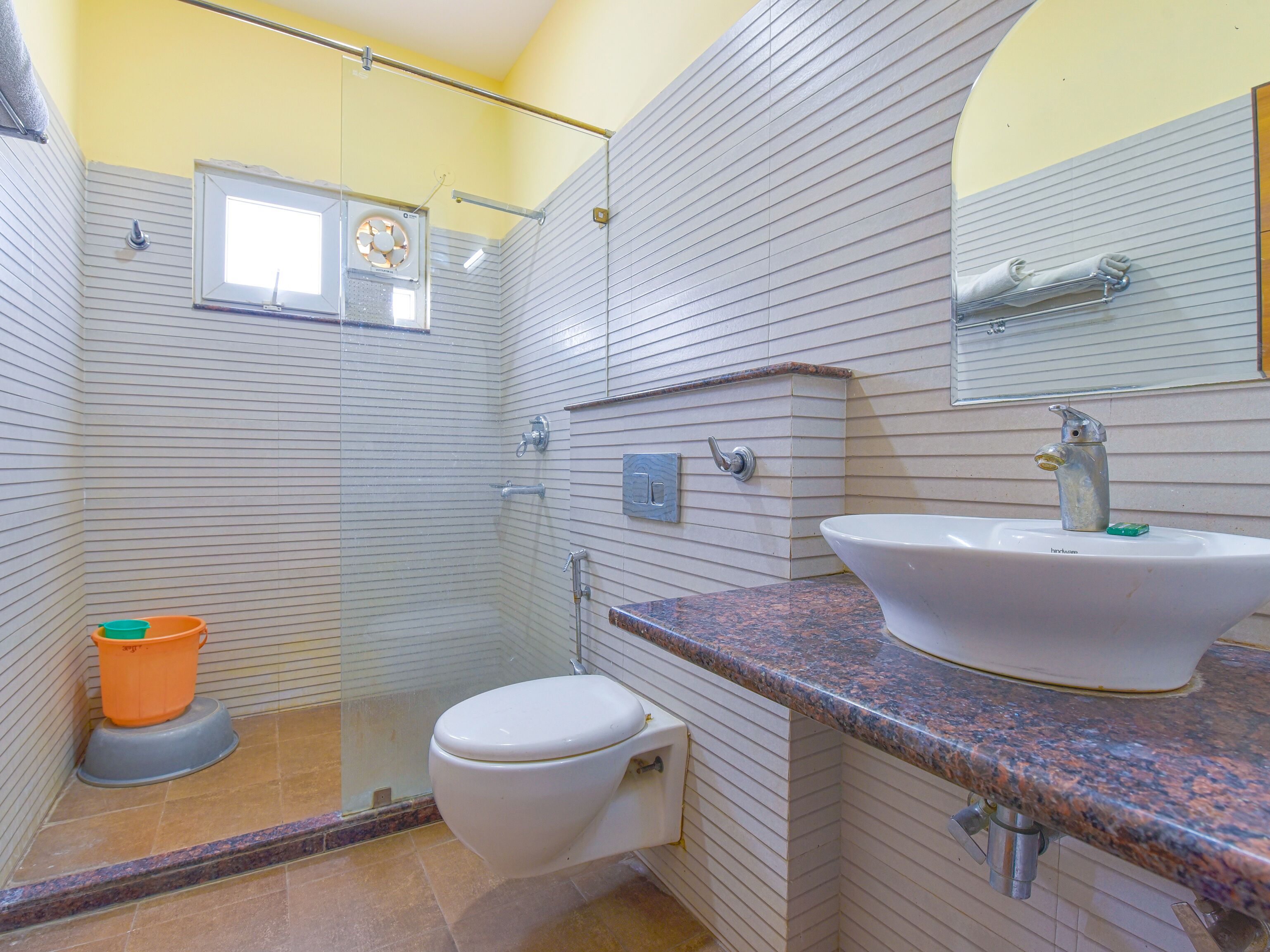 Een badkamer met douche, toilet, wastafel en spiegel.