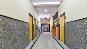 A hallway with marble flooring, yellow doors, and a ceiling fan.