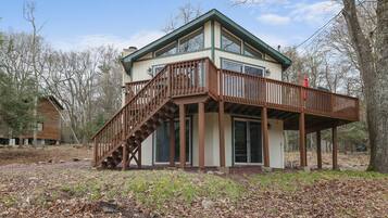 A two-story house with a wooden deck and a staircase leading to the upper floor.