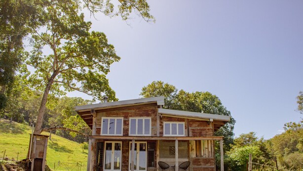 A two-story house with a large front porch, sliding glass doors, and a covered patio area.