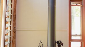 A room with a wood-burning stove, a window with blinds, and a door with a wooden frame.