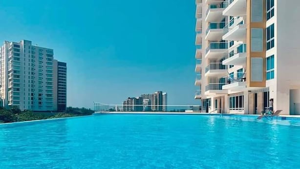 A swimming pool with modern buildings in the background. - Magico Apt 1401 Bello Horizonte (Santa Marta)