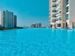 A swimming pool with modern buildings in the background. - Magico Apt 1401 Bello Horizonte (Santa Marta)