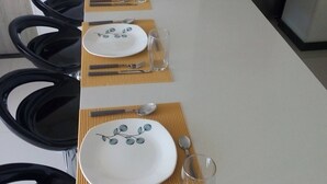 A dining table set with plates, cutlery, and glasses, with chairs around it. - Magico Apt 1401 Bello Horizonte (Santa Marta)