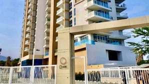 A high-rise residential building with multiple balconies, a gated entrance, and a visible logo on the side. - Magico Apt 1401 Bello Horizonte (Santa Marta)