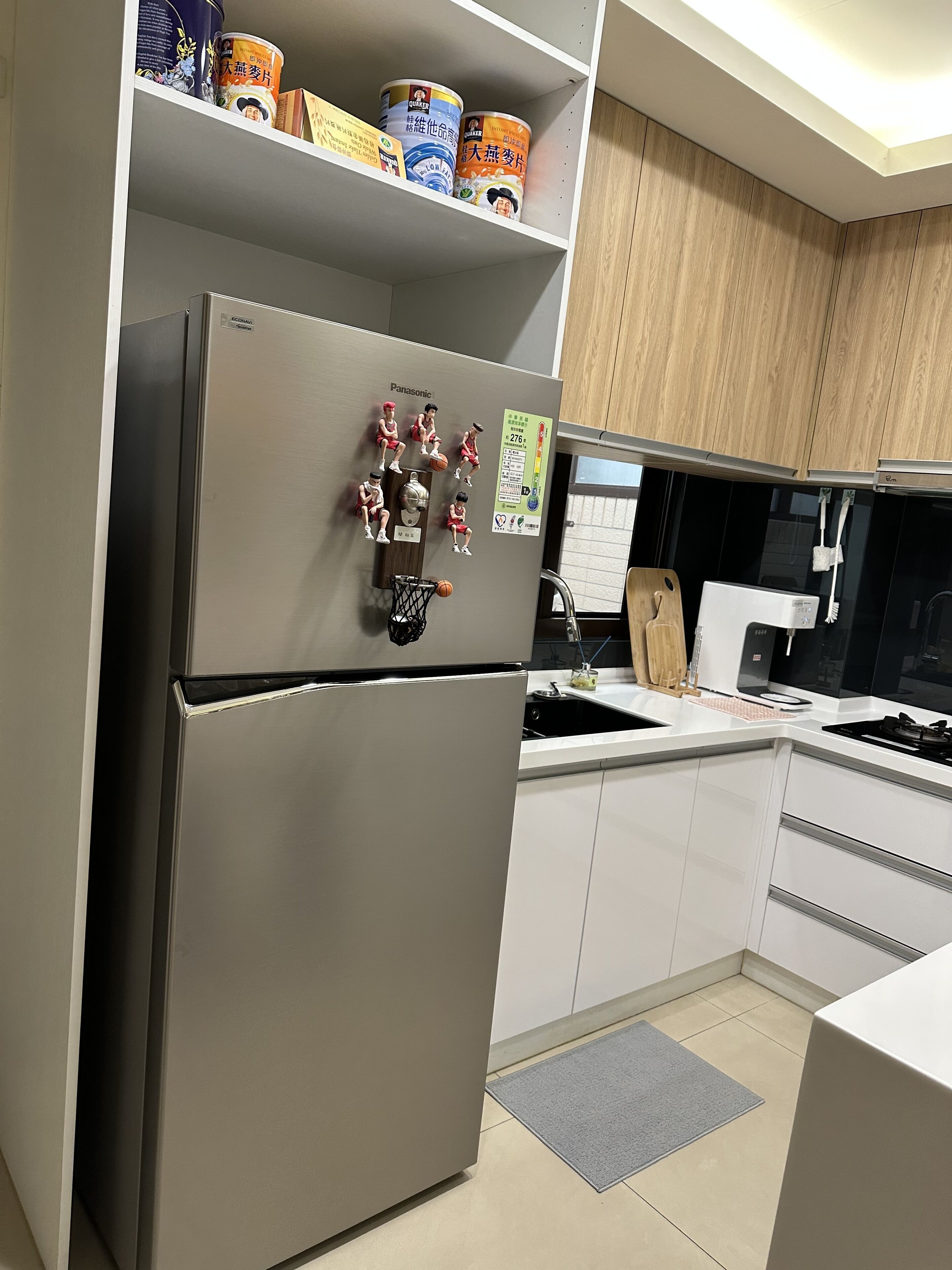 A modern kitchen with a stainless steel refrigerator, wooden cabinets, and a built-in oven.