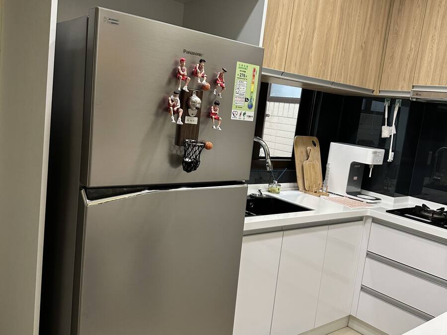 A modern kitchen with a stainless steel refrigerator, wooden cabinets, and a built-in oven.