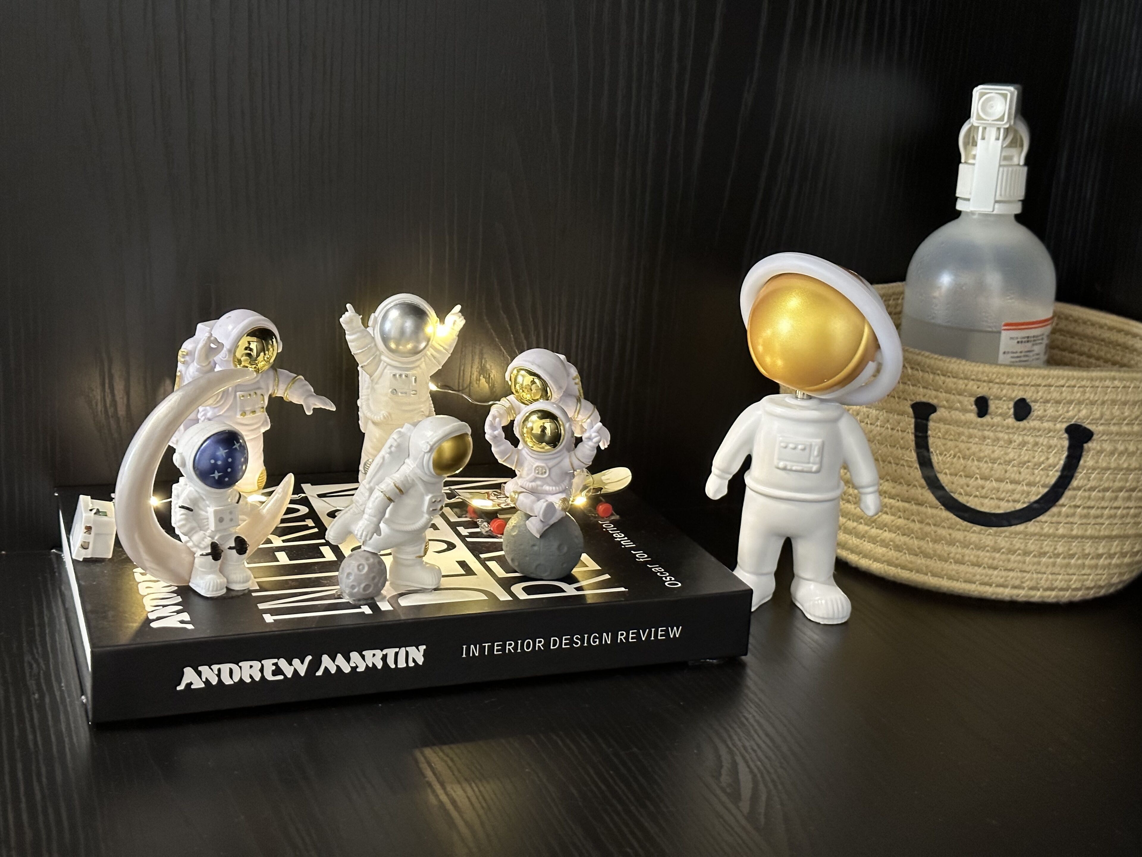 Un libro titulado 'Andrew Martin Interior Design Review' con figuritas de astronautas sobre un pedestal negro.