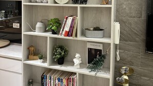 Una estantería bien organizada con varios objetos decorativos, libros y un reloj.