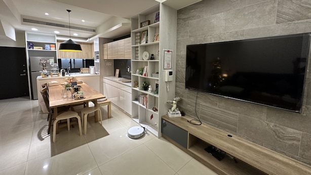 Una cocina moderna con comedor, televisor integrado y robot aspirador.
