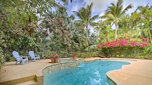 Una piscina con escalones de acceso, rodeada de abundante vegetación y palmeras.